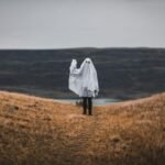 woman in white coat standing on brown grass field during daytime