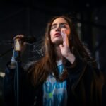 woman performing on stage with closed eyes and holding a microphone