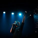 man in black t-shirt singing on stage