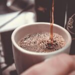 person holding white cup pouring coffee