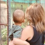 woman in black tank top carrying child in gray denim jacket