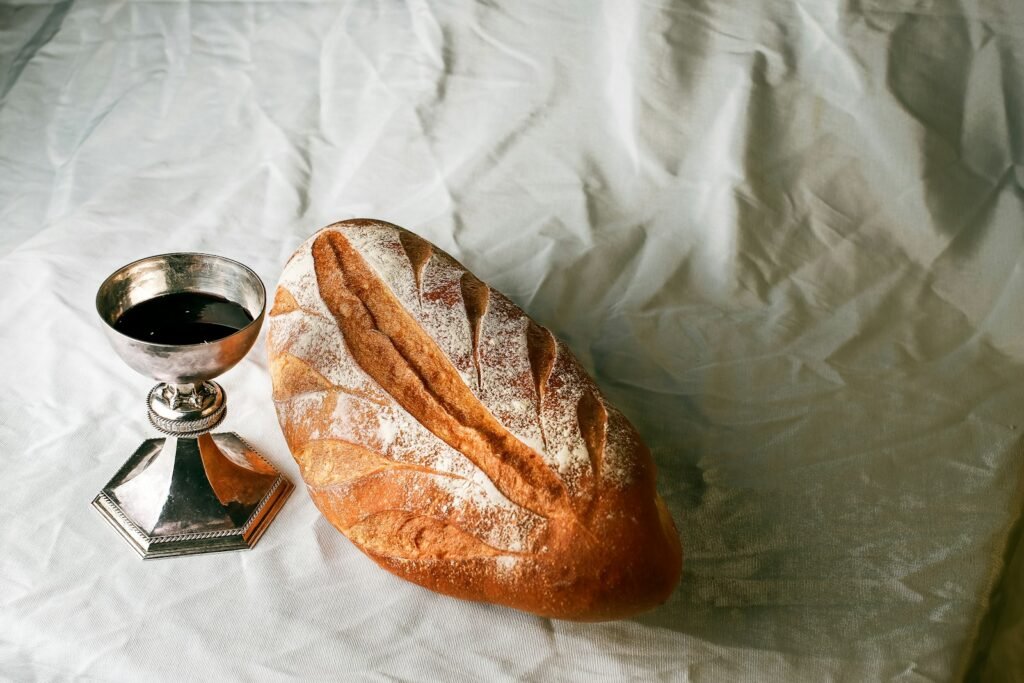 bread on white textile beside clear glass mug - Bible Verses About Communion