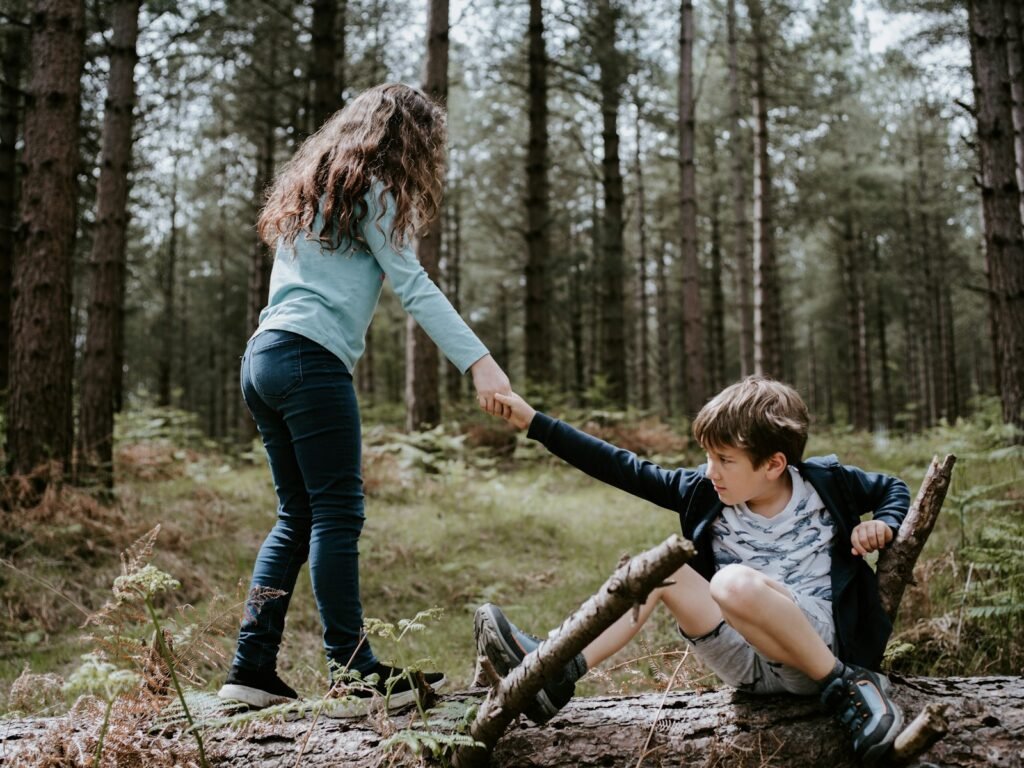 boy and girl playing on three tree log - what does the bible say about helping others