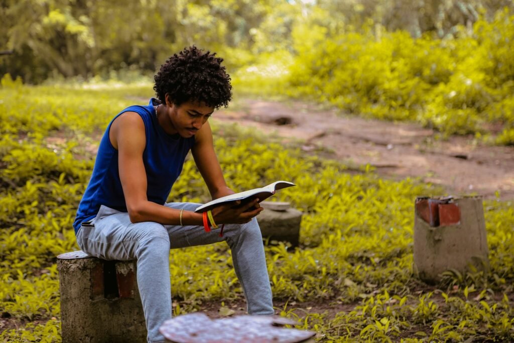 man wearing blue shirt sitting on the bench reading book - who is zerubbabel in the bible