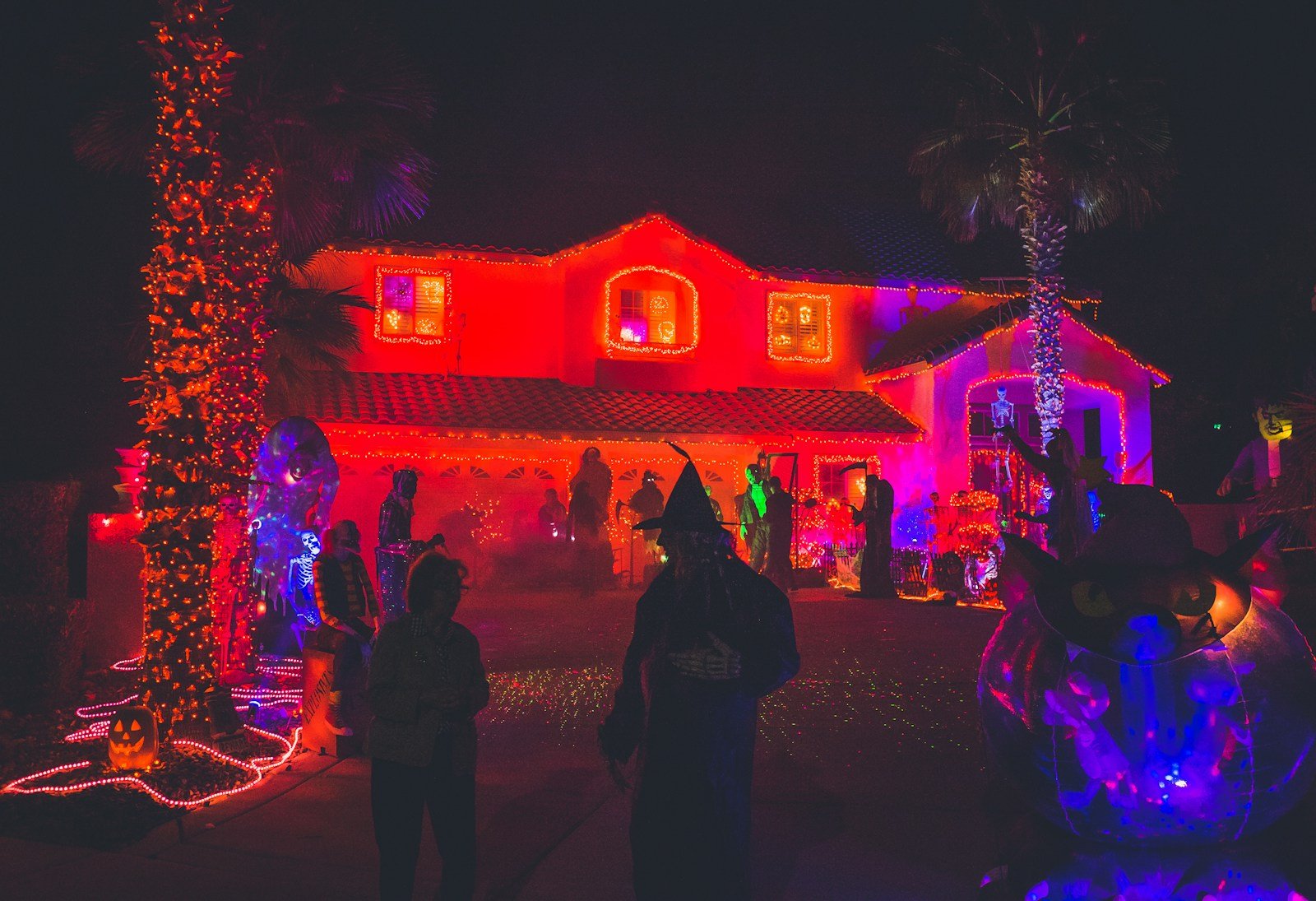 people standing near house with red light decor during night time - is it a sin to celebrate halloween as a christian