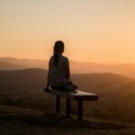 woman sitting on bench over viewing mountain - what does the bible say about meditation