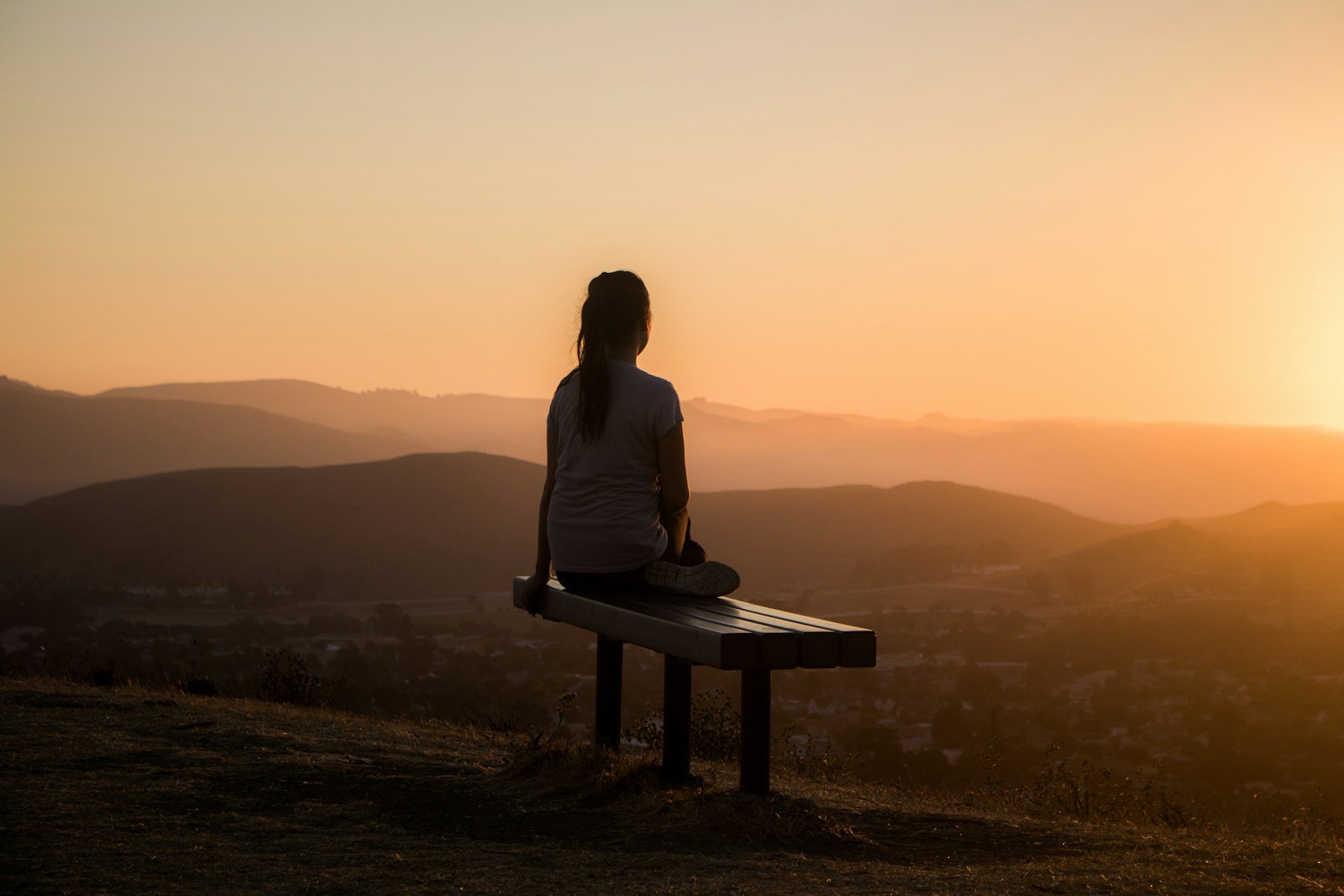 woman sitting on bench over viewing mountain - what does the bible say about meditation